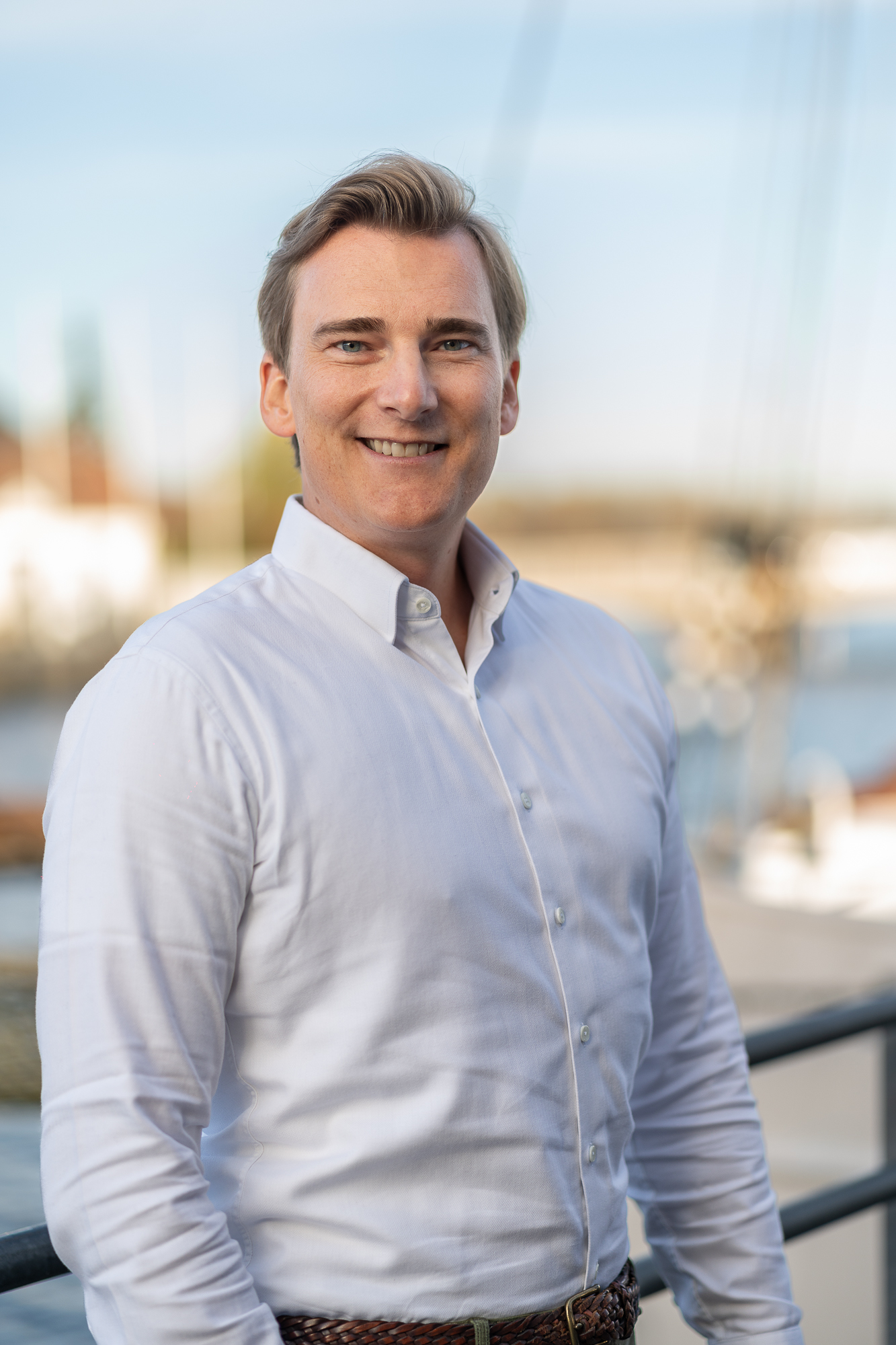 Geschäftsführer der Steuerkanzlei steht im Außenbereich vor maritimer Kulisse.