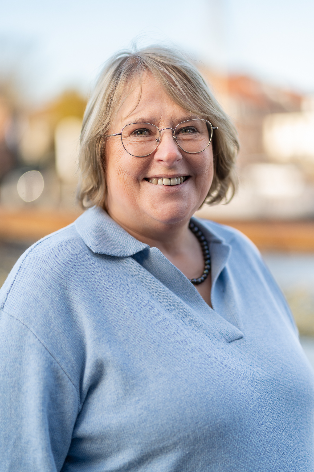 Mitarbeiterin der Steuerkanzlei vor unscharfem Hafenpanorama.